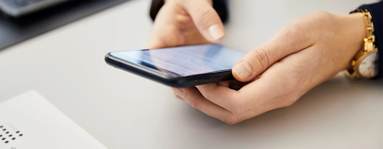 Das Bild zeigt eine Person, die mit dem Mobiltelefon eine Online-Bewerbung absendet.